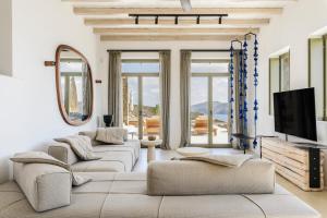a living room with couches and a flat screen tv at Nasta Suites & Villas Intentional Living Mykonos in Mýkonos City