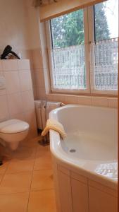 baño con bañera, aseo y ventana en Galeriecafe und Pension Ambiente, en Zittau