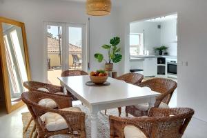 a dining room with a white table and wicker chairs at Casinha do Sol in Almancil