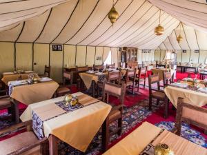 restauracja ze stołami i krzesłami w namiocie w obiekcie Merzouga Luxury Tented Camp w mieście Merzouga