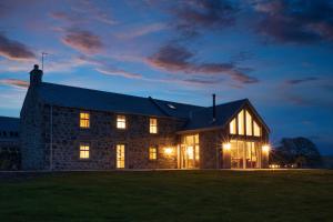 a stone house at night with its lights on at Kipney Farmhouse - luxury hunting lodge in Perth