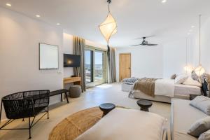 Nasta Suites & Villas Intentional Living Mykonos في مدينة ميكونوس: غرفة نوم بسرير واريكة وطاولة