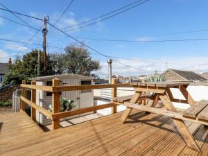 a wooden deck with a wooden picnic table on it at Pepperpot Cottage in Bude