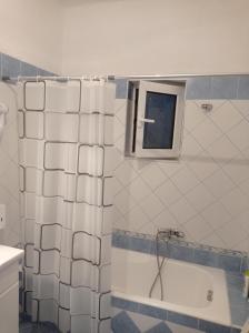 La salle de bains est pourvue d'un rideau de douche et d'une baignoire. dans l'établissement Alex apartment, à Saranda