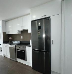 een roestvrijstalen koelkast in een keuken met witte kasten bij Apartamento Playa chica, vistas al mar Lanzarote in Puerto del Carmen