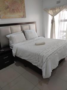 ein Schlafzimmer mit einem großen Bett mit weißer Bettwäsche und Kissen in der Unterkunft S.K.E Guest House in Roodepoort