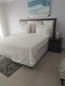 ein großes weißes Bett mit weißer Bettwäsche und Kissen in der Unterkunft S.K.E Guest House in Roodepoort