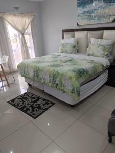 ein Schlafzimmer mit einem Bett mit einer grünen Bettdecke in der Unterkunft S.K.E Guest House in Roodepoort