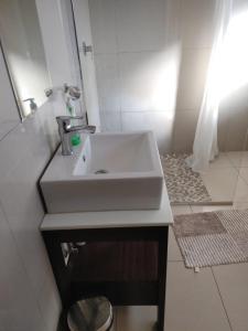 ein Badezimmer mit einem weißen Waschbecken und einem Spiegel in der Unterkunft S.K.E Guest House in Roodepoort