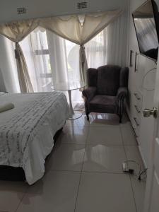 ein Schlafzimmer mit einem Bett, einem Stuhl und einem Fenster in der Unterkunft S.K.E Guest House in Roodepoort