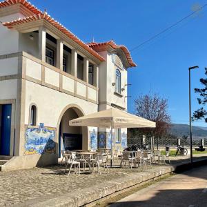 un tavolo con sedie e un ombrellone di fronte a un edificio di Estação Ferroviária de Mondim de Basto a Celorico de Basto