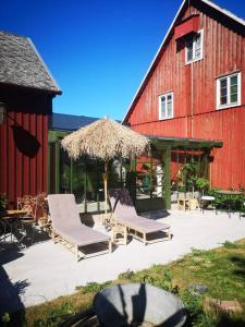 Deux chaises et un parasol à côté d'une grange rouge dans l'établissement Mojo organic spa, à Borgholm