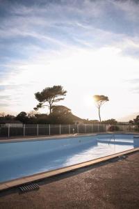 a large swimming pool with the sun in the background at T3 dans résidence avec piscine in Six-Fours-les-Plages