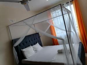 1 cama con dosel en una habitación con ventana en La Grande 1bedroom Apartment Mtwapa, en Mtwapa