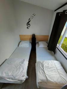 2 camas en una habitación pequeña con un signo de dólar en la pared en Le Cocooning, en Biville-sur-Mer