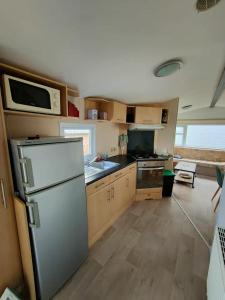 a kitchen with a refrigerator and a microwave at Le Cocooning in Biville-sur-Mer