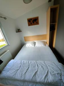 a bedroom with a large white bed with a window at Le Cocooning in Biville-sur-Mer