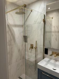 eine Dusche mit Glastür neben einem Waschbecken in der Unterkunft Lazurowy Apartament in Łeba + 25 Fotos