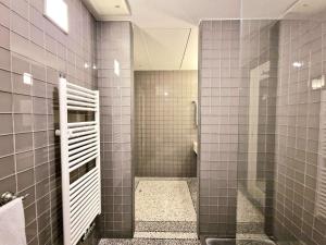 bagno con doccia e pareti rivestite con piastrelle grigie di Roccobarocco Boutique Hotel a Ischia