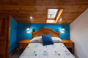 een slaapkamer met blauwe muren en een bed met een houten hoofdeinde bij Casa Rural Besolí in Areu