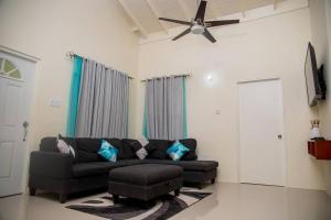 a living room with a couch and a ceiling fan at Entire residential home • Trelawny• Smalls Villa in Florence Hall