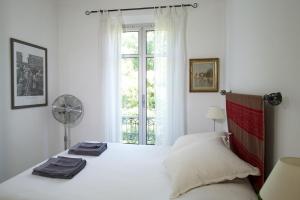 a white bedroom with a bed and a window at Rue Sade Bed & Breakfast in Antibes