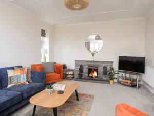 a living room with a blue couch and a fireplace at Gwynant - Bull Bay in Amlwch