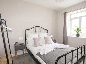 a white bedroom with a large bed with white pillows at Gwynant - Bull Bay in Amlwch