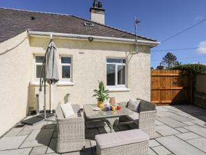 a patio with a table and chairs in front of a house at Gwynant - Bull Bay in Amlwch