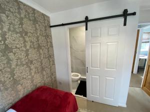 a bedroom with a white door and a toilet at Stylish 4 Bedroom House with Private Parking and Free WiFi in Milton Keynes by HP Accommodation in Milton Keynes