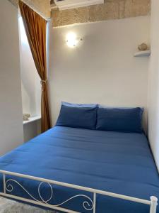 una cama azul en una habitación con ventana en Dimora Serena, en Ostuni