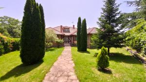 una casa con un jardín con árboles y un camino en El huerto de la Reina, en Becerril de la Sierra