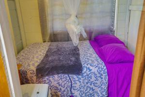 een slaapkamer met een bed met paarse lakens en een raam bij My Little Cabin In Negril, cabin in Negril