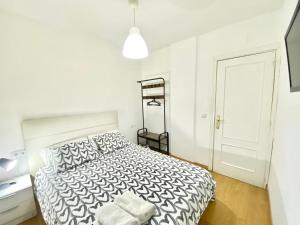 a white bedroom with a bed and a black and white comforter at Jaime el Conquistador Apartment in Madrid