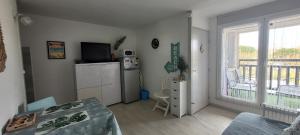 a living room with a television and a kitchen with a balcony at Palm Appart in Biscarrosse-Plage