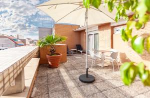 un patio con tavolo e ombrellone su un balcone di Hotel Derby a Barcellona