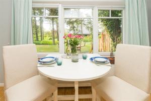 mesa de comedor blanca con 2 sillas y ventana en Bandomir-Bungalow-Wohnung-02, en Westerland