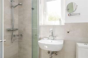 Un baño con lavabo y ducha con espejo. en Bandomir-Bungalow-Wohnung-02, en Westerland
