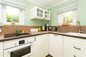 Una cocina con gabinetes blancos y un fregadero. en Bandomir-Bungalow-Wohnung-02, en Westerland