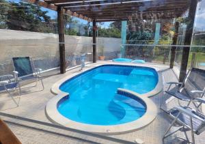 a swimming pool on a patio with chairs and a table at Flat Dona Branca Piscina Aquecida e Vista do Pôr do Sol in Alto Paraíso de Goiás