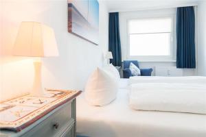 ein Schlafzimmer mit einem Bett und einem Tisch mit einer Lampe in der Unterkunft Haus Ankerlicht 3.OG Wohnung 43 in Westerland