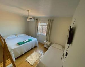 Schlafzimmer mit einem weißen Bett und einem Flachbild-TV in der Unterkunft Pousada do beco in Caravelas