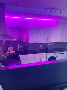 uma cozinha com luzes cor-de-rosa nos balcões em Elegant studio1 netflix bathroom close to beach em Swansea