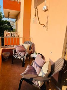 balkon z 2 krzesłami i stołem z poduszkami w obiekcie Eloro casa vacanza w mieście Noto Marina