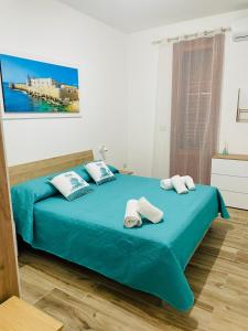sypialnia z niebieskim łóżkiem i ręcznikami w obiekcie Eloro casa vacanza w mieście Noto Marina