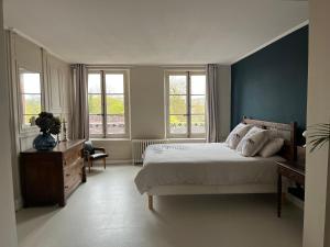 um quarto com uma cama grande e janelas em Maison d'hôtes l'Évidence em Rugles