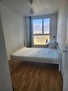 łóżko w pokoju z dużym oknem w obiekcie Appartement T4 très spacieux w Grenoble
