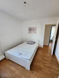 białe łóżko w pokoju z drewnianą podłogą w obiekcie Appartement T4 très spacieux w Grenoble