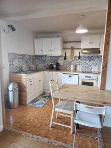 kuchnia z drewnianym stołem i białymi szafkami w obiekcie Appartement T4 très spacieux w Grenoble