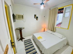 a bedroom with a white bed and a window at Pousada do beco in Caravelas